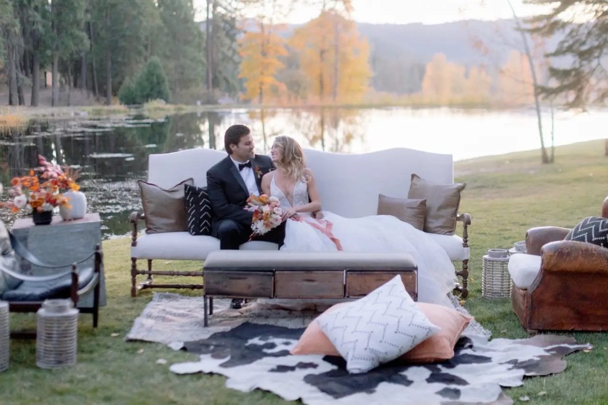 A wedding couple at the Greenhorn Ranch in Northern California sitting on a rustic sofa by the lake