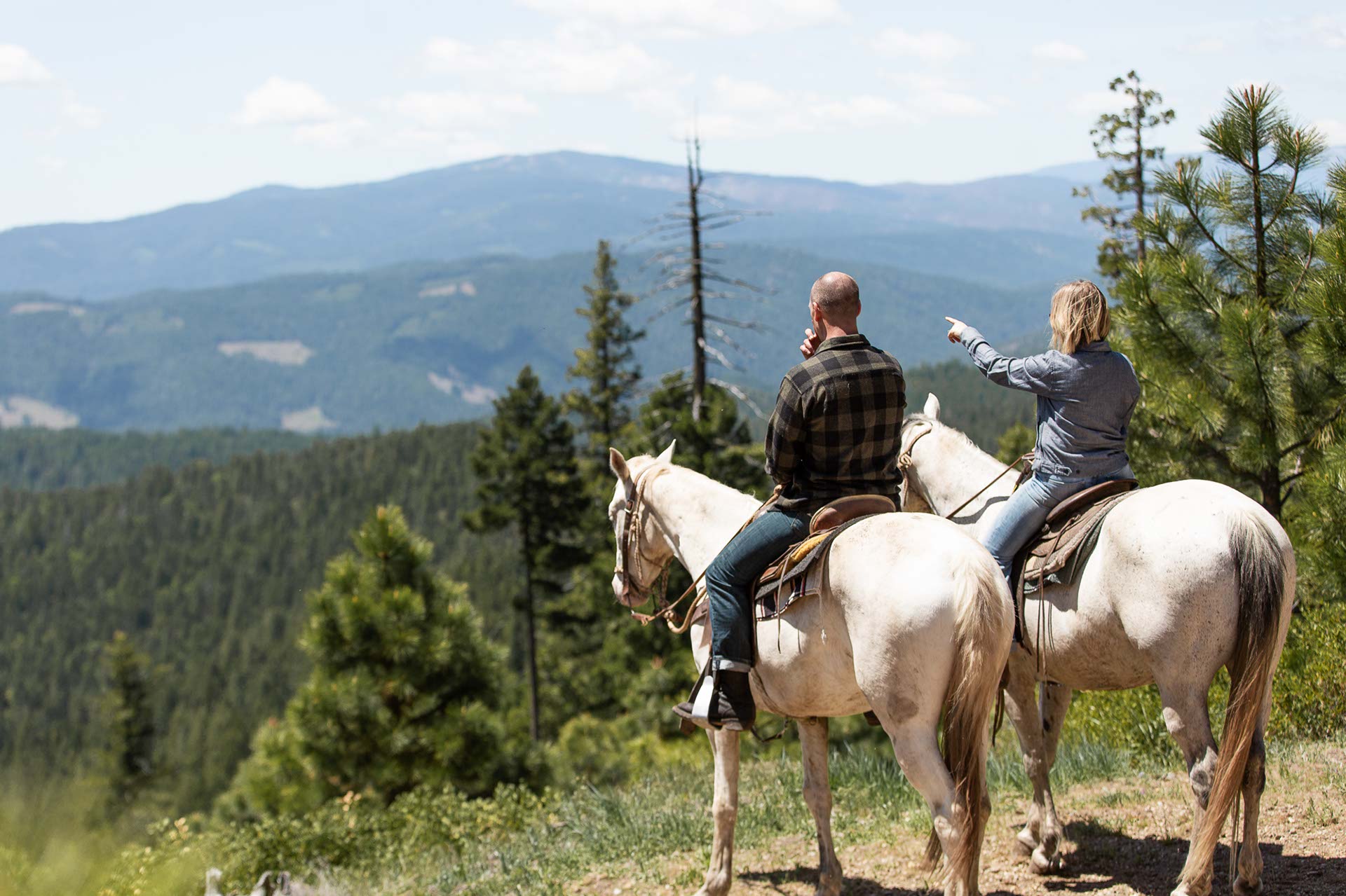 A couple on a horseback ride overlooking the mountains of California at the Greenhorn Ranch in Quincy, CA